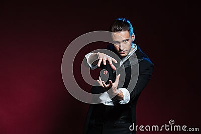 Concentrated young man magician conjuring tricks with red dice Stock Photo