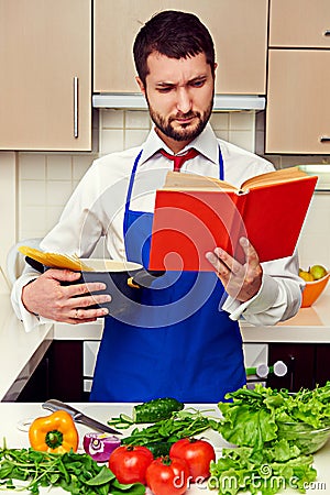 Concentrated young man reading cookbook Stock Photo
