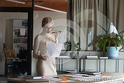 Concentrated young manager using virtual assistant on phone. Stock Photo