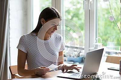 Concentrated young woman paying utility bills online. Stock Photo