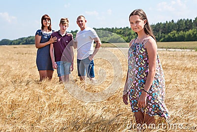 Concept of adopted child, young girl standing on foreground with adoptive family on background, stepdaughter with father, mother Stock Photo