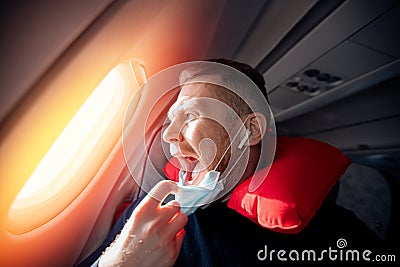 Concept aerophobia or aviophobia. Afraid of fear flying on airplane and height tourist man in safe medical mask Stock Photo