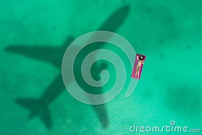 Concept of airplane travel to exotic destination with shadow of commercial airplane flying above beautiful tropical beach. Beach Stock Photo