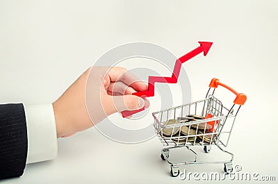 The concept of attracting investments, increasing the average check in the store. The businessman`s hand holds the arrow up above Stock Photo