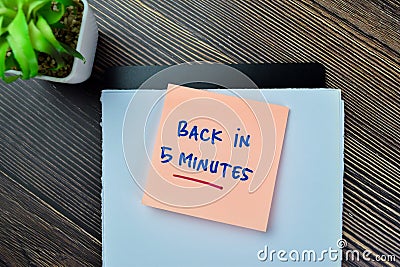 Concept of Back in 5 Minutes write on sticky notes isolated on Wooden Table Stock Photo
