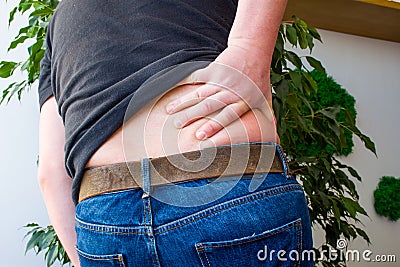 Concept of backaches, back pain or manifestations or symptoms of radiculopathy. Man grabbed with Palm over lumbar region on back, Stock Photo