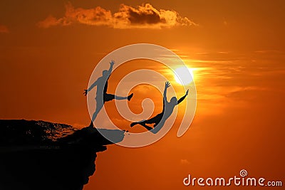 The concept of betrayal and the help of friends, Silhouette of Men are jumped between high cliff at a red sky sunset Stock Photo