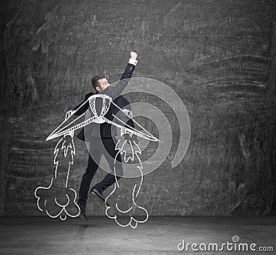 A concept of business angel. A man is flying over the black chalkboard. Stock Photo