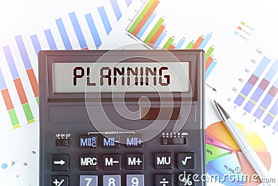 On the table are financial charts and a calculator, on the electronic board of which is written the text - PLANNING Stock Photo