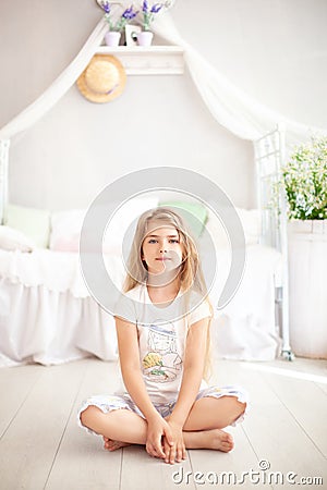 The concept of childhood and health. The child does yoga and meditation at home. A little blonde girl in pajamas sits in a pose fo Stock Photo