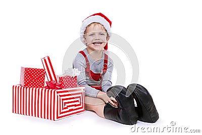 Concept: Christmas in childhood. Kid in red costume of dwarf with gifts Stock Photo