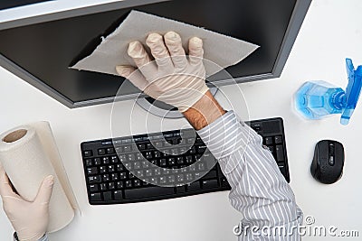 Concept of cleaning or disinfecting the office - a businessman cleans the workplace, computer, desk, uses a spray gun and paper Stock Photo