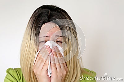 Sick woman sneezing and blowing her nose in a handkerchief Stock Photo