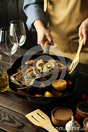 Concept of cooking, female chef cooked dish with artichoke Stock Photo