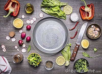 Concept cooking vegetarian food ingredients laid out around the pan with a knife spices space for text on rustic wooden backgr Stock Photo