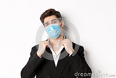 Concept of covid-19, business and social distancing. Image of confident handsome man in trendy suit and medical mask Stock Photo