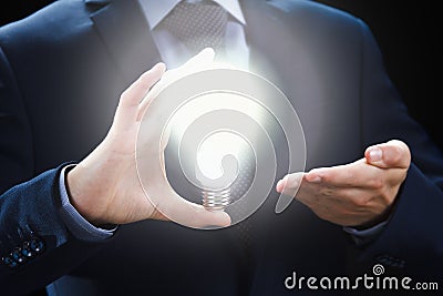 Concept of creative and inspiration idea. Hands of businessman holding illuminated light bulb. Stock Photo