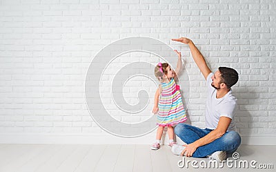 Concept. Dad measures growth of her child daughter at a wall Stock Photo