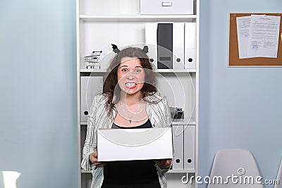 Concept of dismissal from work. Wicked woman with carton box with her stationery stuff, girl was fired from her job. Stock Photo