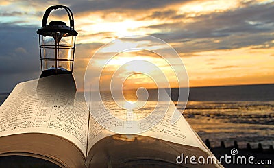 Bible lantern lamp light lamplight divine spiritual book open sky beach sea ocean Stock Photo