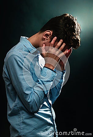 The concept of domestic violence. A teenage boy covers his face with his scratched hands, experiencing stress. Vertical Stock Photo