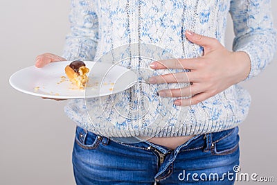 Concept of eating too much of sweets. Cropped closeup photo of cheerful girl enjoying eating sweets holding almost empty plate in Stock Photo