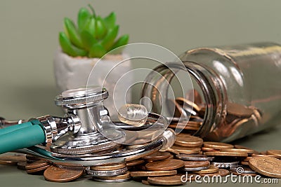 The concept of economy and medicine costs health. Pile of real coins and stethoscope Stock Photo