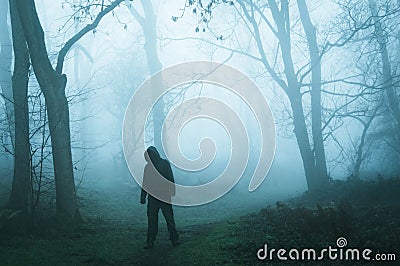 A concept edit of an eerie spooky figure without a face, standing in a foggy winters forest Stock Photo