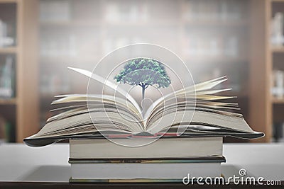 The concept of education by planting a tree of knowledge in the opening of an old book in the library and the magical magic of lig Stock Photo