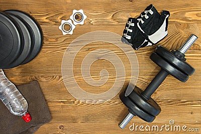 Concept for exercise and sport. Dumbbell, gloves, towel and bottle water on a wooden background Stock Photo