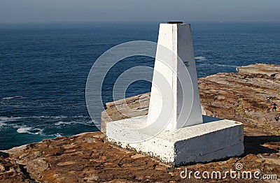 Concept of exploration. Waterfront lookout on cliff edge with white obelisk marker and idyllic and amazing vista of sea Stock Photo