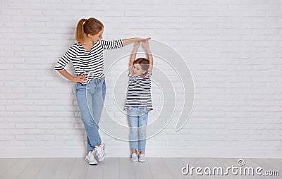 concept of the family. mother measures growth of child to daughter near empty wall Stock Photo