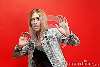 The concept of fear, horror, fright. The modern young lady in fear tries to fence off her hands, with a frightened face Stock Photo