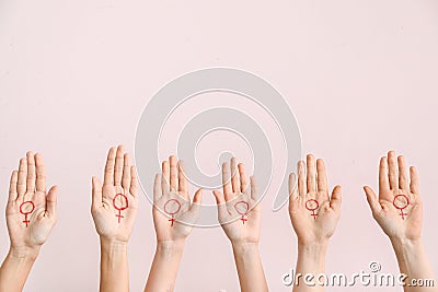 Women with drawn symbols of woman on their palms against color background. Concept of feminism Stock Photo