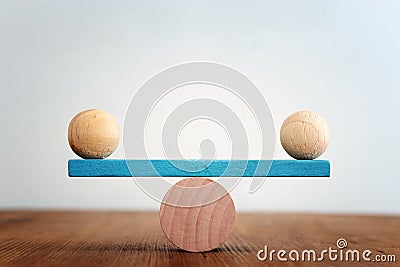 Concept of finding the right balance. Wooden balls on seesaw Stock Photo