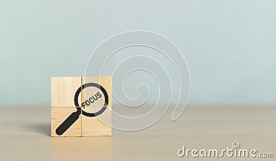 Concept Focus Target. Wooden block cube with magnifier glass and word FOCUS. Discovery search goal success Stock Photo