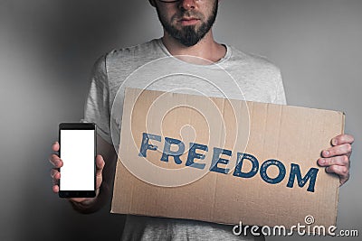 Concept of freedoms and human rights. A man with a cardboard and a phone in his hand. Text freedom and mock up. Dark color Stock Photo