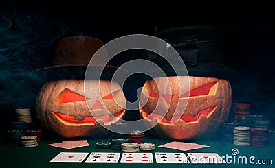 The concept of Halloween. Evil scary pumpkins play poker in hats Stock Photo