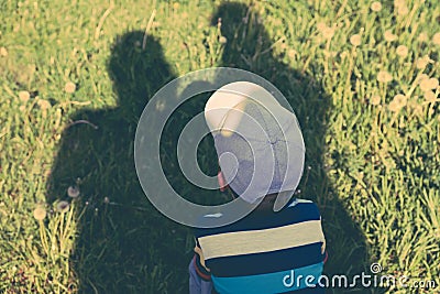 Concept of family. Shadows of parents, father and mother protect the child from the scorching sun. Stock Photo