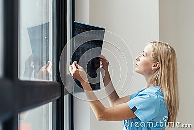 Serious nurse in medical uniform looking at x ray picture Stock Photo