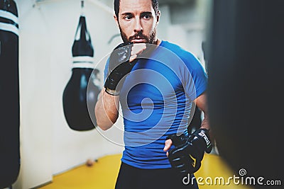 Concept of a healthy lifestyle.Young muscular man fighter practicing kicks with punching black bag.Kick boxer boxing as Stock Photo