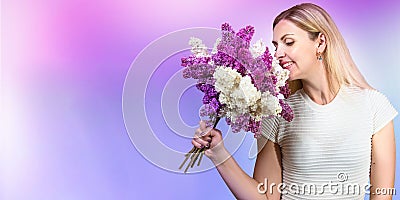 A beautiful young woman inhales the aroma of a spring bouquet of lilac. The concept of the holiday. Stock Photo