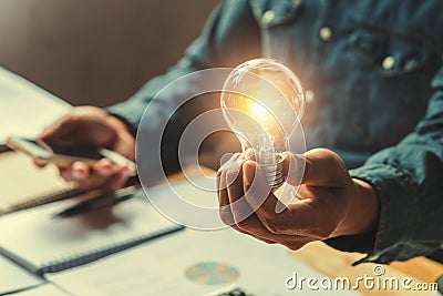 Concept idea saving energy. businessman hand holding lightbulb i Stock Photo