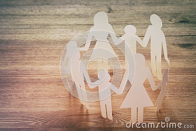 concept image of Family paper chain cutout holding hands, over wooden table. Stock Photo