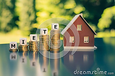 Concept of increasing rents. Dice placed on stacks of coins form the German word `miete` `rent` in English Stock Photo