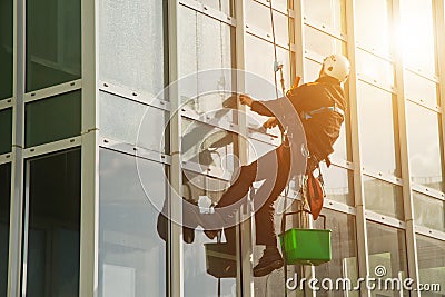 Concept of industry urban works. Industrial mountaineering worker in uniform hangs over residential facade building Stock Photo