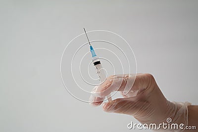 The concept of inoculation, vaccination or treatment of the disease. Close-up of the doctor`s gloved hand holding a medical syring Stock Photo