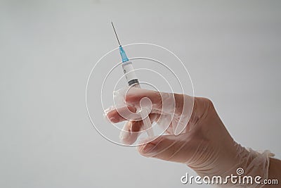 The concept of inoculation, vaccination or treatment of the disease. Close-up of the doctor`s gloved hand holding a medical syring Stock Photo