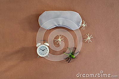 Concept of insomnia and nightmare disorder, flat lay. Sleeping mask, alarm clock and spiders. Unhealthy sleep Stock Photo