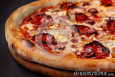 The concept of Italian cuisine. Real Italian pizza on a thin cake with large sides on a black background. Close up. Background Stock Photo